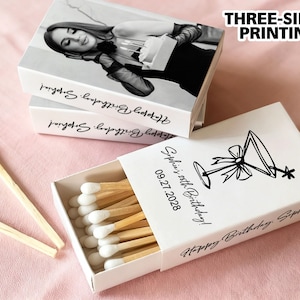 May include: White matchboxes with custom printing. One box is open, revealing wooden matches with white tips. The boxes feature a black and white photo, a martini illustration, and the text "Happy Birthday Sophia!" and "Sophia's 20th Birthday!"