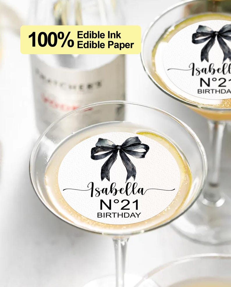 K&ouml;nnte beinhalten: Zwei runde essbare Papier-Cupcake-Topper mit einer schwarzen Schleife und dem Text "Isabella N&deg;21 Birthday".