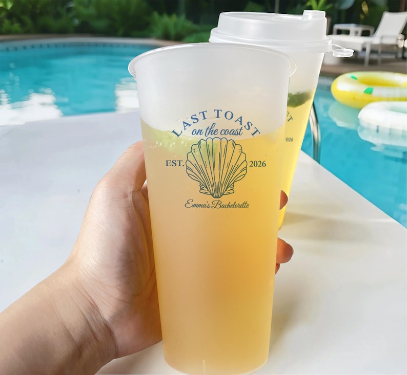 K&ouml;nnte beinhalten: Ein durchsichtiger Plastikbecher mit einem gelben Getr&auml;nk. Der Becher hat ein blaues und wei&szlig;es Design mit dem Text "Last Toast on the Coast", einer Muschelgrafik und dem Text "Est. 2026 Emma's Bachelorette".