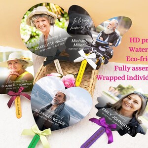 May include: A set of five memorial fans with black handles and colorful ribbons. Each fan features a photo of a person and their name, dates of birth and death, and the phrase "In loving memory of".
