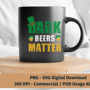 May include: A black coffee mug with a green leprechaun hat and the text "Dark Beers Matter" in green and yellow letters. The mug is sitting on a wooden coaster.