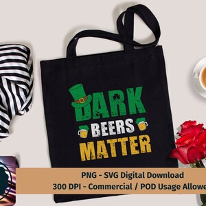 May include: A black tote bag with a green shamrock and the text "Dark Beers Matter" in a distressed font. The bag is on a white surface with a striped scarf and a cup of coffee.