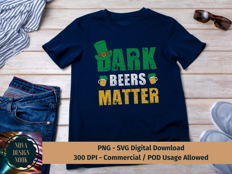 May include: A dark blue t-shirt with a green, white, and gold graphic design. The graphic features a leprechaun hat, beer mugs, shamrocks, and the text "Dark Beers Matter".