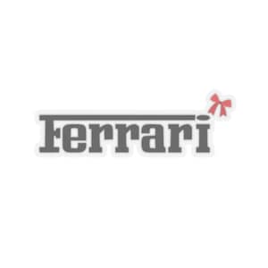 May include: A grey sticker featuring the word "Ferrari" in a bold, sans-serif font. A red bow is in the upper right corner. The sticker is set against a white backdrop.