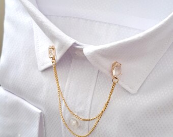 May include: A gold collar pin with two clear crystal stones and a double chain.