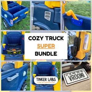 May include: A blue and yellow toy truck with a steering wheel, a working horn, and a seat. The truck has a number plate that says "LET THE GOOD TIMES ROLL VROOM!" and a sticker that says "TINKER LABS PURE 3D IMAGINATION".
