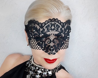 May include: A black lace eye mask with rhinestones. The mask has a delicate floral pattern and covers the eyes and bridge of the nose.