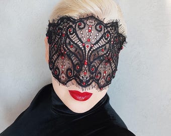 Könnte beinhalten: Eine schwarze Spitzenmaske mit roten Strasssteinen. Die Maske bedeckt die Augen und einen Teil der Stirn.