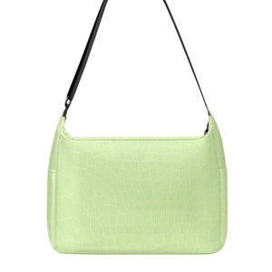 May include: A pale green shoulder bag with a black strap. The bag features a textured pattern and a rectangular shape with curved corners. The strap is thin and adjustable.