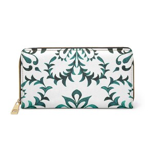 Könnte beinhalten: Weißes Portemonnaie mit tealfarbenem Blumenmuster und goldenem Reißverschluss. Das Portemonnaie ist rechteckig und hat eine strukturierte Oberfläche. Das florale Design ist symmetrisch.