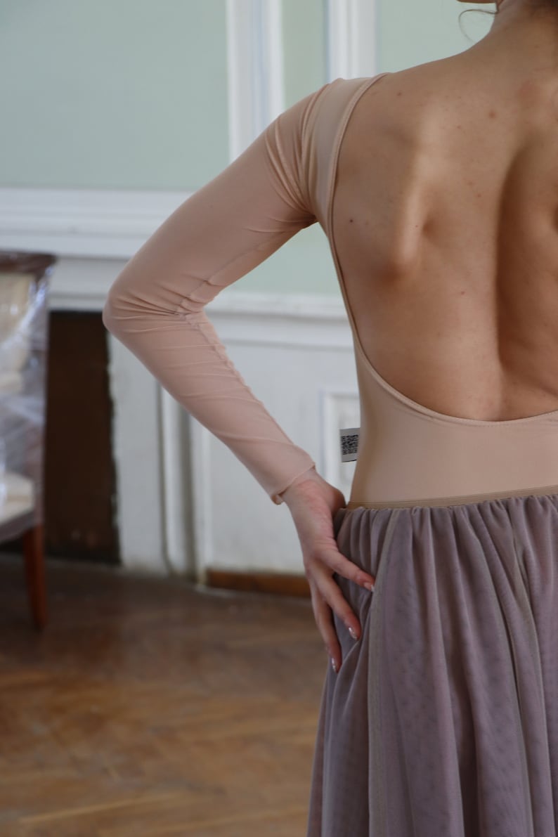 K&ouml;nnte beinhalten: Eine Frau tr&auml;gt einen hautfarbenen Body mit langen &Auml;rmeln und tiefem R&uuml;cken. Der Body wird mit einem langen, flie&szlig;enden, staubigen rosafarbenen T&uuml;llrock kombiniert.