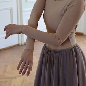 K&ouml;nnte beinhalten: Eine Frau tr&auml;gt einen lang&auml;rmeligen, hautfarbenen Trikot und einen langen, flie&szlig;enden, mauvefarbenen T&uuml;llrock.