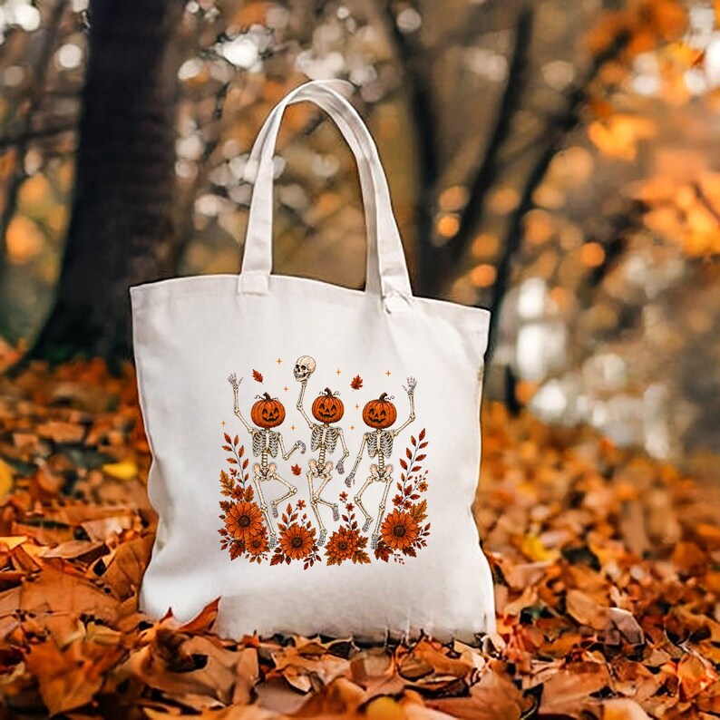 Natural cream canvas tote bag showcasing the Wildflower Skeleton design among autumn leaves and botanical skeleton details.