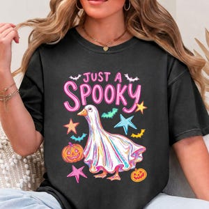 Halloween Goose displayed on a washed black short sleeve t-shirt. A bright funny halloween and ghost goose design for trendy seasonal shirts.