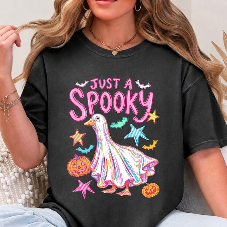 Halloween Goose displayed on a washed black short sleeve t-shirt. A bright funny halloween and ghost goose design for trendy seasonal shirts.