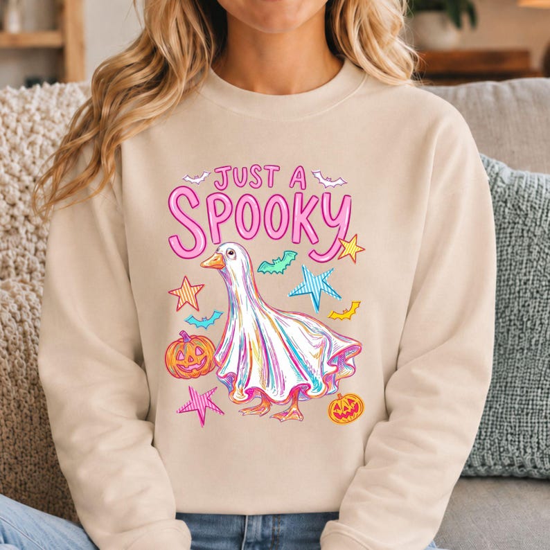 Halloween Goose shown on a cream crewneck sweatshirt. Perfect for girly halloween, pastel halloween, and cozy spooky season style.