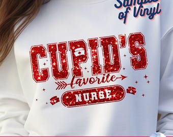 以下が含まれることがあります： 赤いキラキラ文字で「Cupid's Favorite Nurse」と書かれた白いスウェットシャツ。デザインには看護師の帽子アイコンと矢印のアクセントが含まれています。「Sample of Vinyl」という言葉が右上隅にあります。