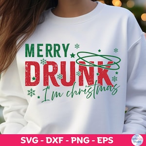 May include: White sweatshirt with the text "MERRY DRUNK I'm christmas" in green and red. The design includes snowflakes and a green graphic. The sweatshirt is a festive holiday apparel item.