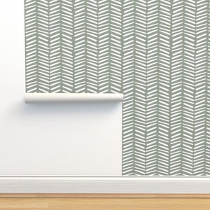 May include: A roll of wallpaper with a white herringbone pattern on a sage green background.