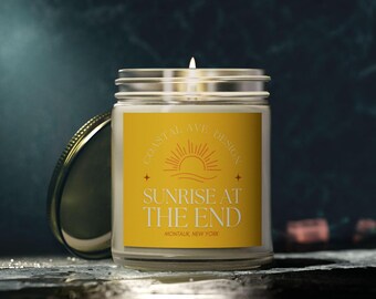 Puede incluir: Un tarro de vela amarillo con una etiqueta blanca que dice "Sunrise at the End" y "Montauk, New York". La etiqueta también presenta un gráfico de sol estilizado y el texto "Coastal Ave Design".