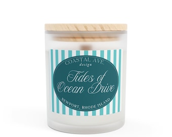 May include: A white candle jar with a wooden lid. The label features a teal blue circle with white text that reads "Coastal Ave. design Tides of Ocean Drive Newport, Rhode Island" on a white and teal blue striped background.