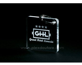 以下が含まれることがあります： 透明なアクリル製のキーホルダーで、白く刻まれたロゴには「Grand Hotel Lamezia」と「GHL」が書かれており、ロゴの上に4つの星があります。キーホルダーには「www.plexdaautore.com」というウェブサイトも刻まれています。