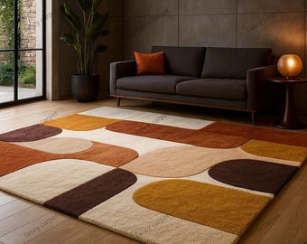 May include: A rectangular area rug with an abstract design in shades of brown, beige, and orange. The rug features large, rounded shapes in varying sizes and colors, creating a modern and inviting aesthetic. The rug is placed on a wooden floor.