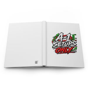 May include: An open white notebook featuring a graphic on the right page with the text A-1 SETUPS ONLY in bold white and red lettering. The design includes green and red candlestick chart elements and a small QR code on the bottom left page.