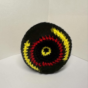 Può includere: Una palla nera all'uncinetto con un motivo a spirale rosso e giallo. Questo articolo fatto a mano può essere utilizzato per la decorazione o come accessorio giocoso. La palla misura circa 10 cm di diametro.