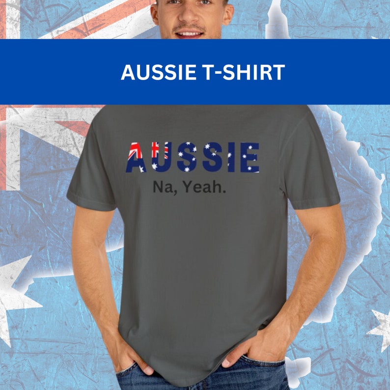 Puede incluir: Camiseta gris con la palabra "AUSSIE" en letras azules, con la bandera australiana incorporada en el dise&ntilde;o. Debajo de la palabra "AUSSIE" est&aacute; la frase "Na, Yeah."