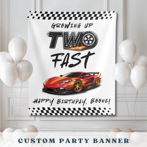 May include: A white custom party banner with a race car theme. The banner features a red and orange sports car with flames, the text "Growing Up Two Fast," and "Happy Birthday, Boone!" in black.