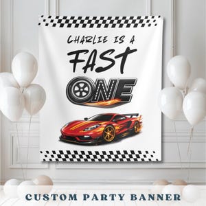 May include: A white custom party banner with a black and white checkered border. The banner features the text "Charlie is a Fast One" above a red sports car with flames and gold wheels. White balloons are in the background.