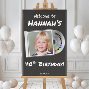 May include: A black sign on a wooden easel reads "Welcome to HANNAH'S 40th BIRTHDAY!" with a photo and a CD graphic. White balloons are in the background. The date 12.18.25 is at the bottom.