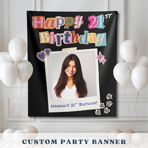 以下が含まれることがあります： カラフルな切り抜き風の文字で「Happy 21st Birthday」と書かれた黒い長方形のパーティーバナー。中央の白いフォトフレームには、長いダークヘアの人物のポートレートと、その下に「Hannah's 21st Birthday」というテキストが表示されています。