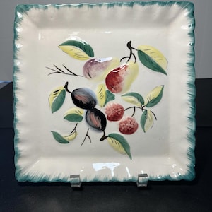 May include: Square ceramic plate with a cream-colored surface and a teal scalloped edge. The plate features a hand-painted design of pears, figs, and berries in shades of red, purple, yellow, and green.