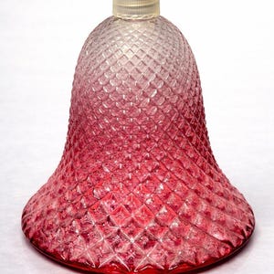 May include: A decorative glass bottle, bell-shaped with a textured surface and a clear stopper. The colour gradient transitions from clear to deep red. The bottle has a diamond pattern across its surface. The base is solid red.