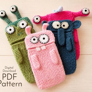 May include: Four colorful crochet monster phone cases in green, pink, blue, and fuchsia. Each case features large, googly eyes and a unique design, including antennae, ears, and teeth. The text "Digital Download PDF Pattern" is visible.