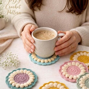 May include: A white ceramic mug filled with coffee rests on a light blue and cream crochet coaster. Several colorful crochet coasters in shades of yellow, pink, and green are also visible. The image includes the text "PDF Crochet Pattern".