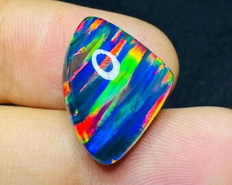 May include: A triangular, iridescent opal gemstone with a blue, green, red, and orange color pattern. The opal has a white, circular inclusion.