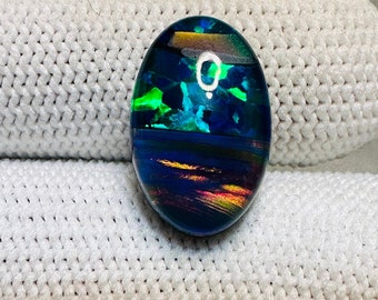 May include: Oval shaped blue, green, and gold opal cabochon with iridescent shimmer.