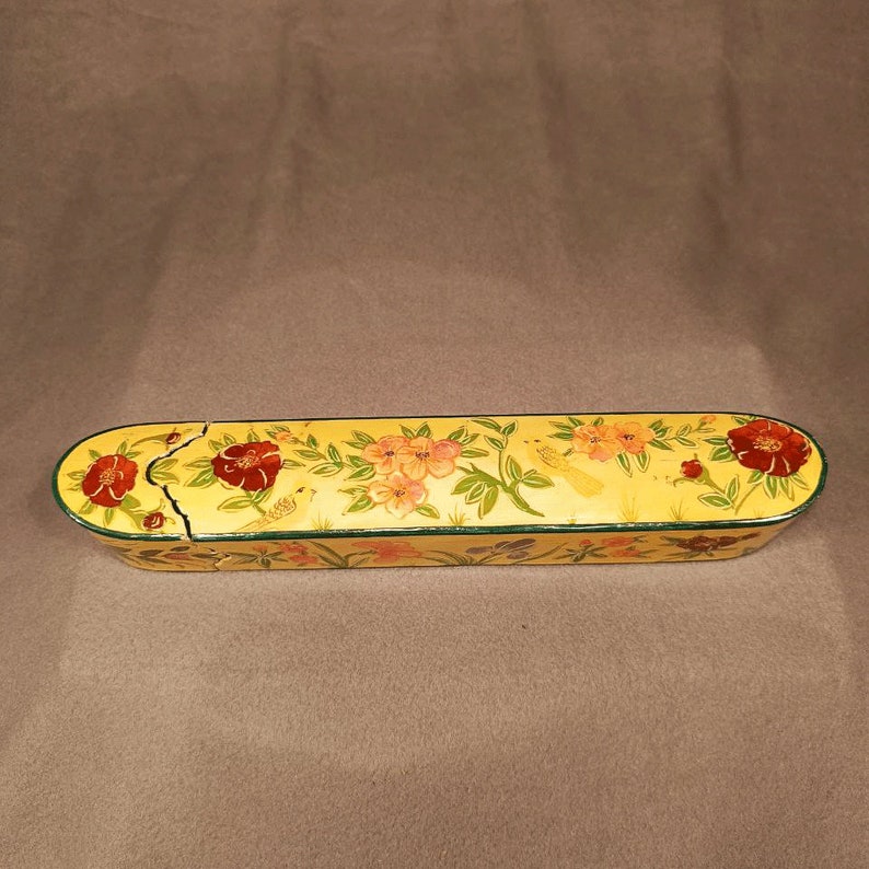 May include: A yellow wooden box with a floral design painted on it. The flowers are red, pink, and yellow, and there are small yellow birds painted on the box as well.