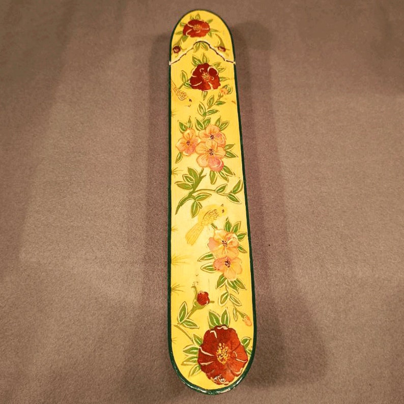 May include: A yellow wooden box with a floral design. The box is decorated with red, pink, and yellow flowers, as well as small yellow birds. The box has a green border.