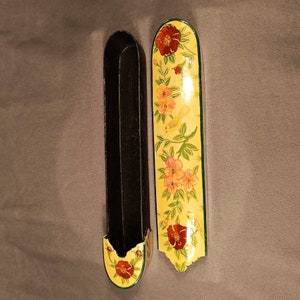 May include: Two decorative boxes with floral designs. One box is black with a floral design on the lid. The other box is yellow with a floral design and a bird on the lid.