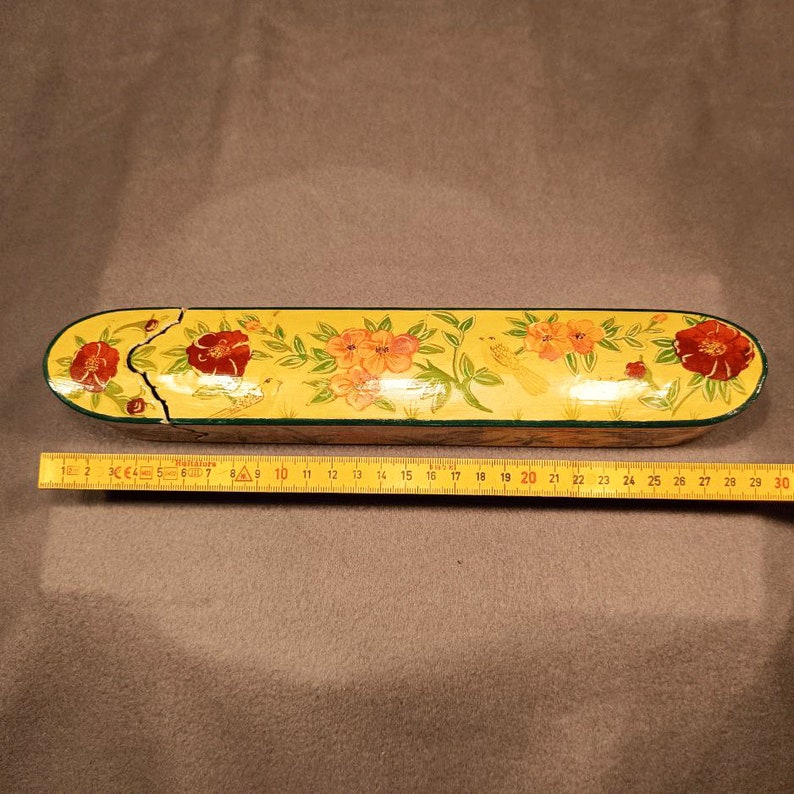 May include: A yellow wooden box with a floral design. The box is decorated with red, orange, and green flowers and birds. The box is approximately 25 inches long.