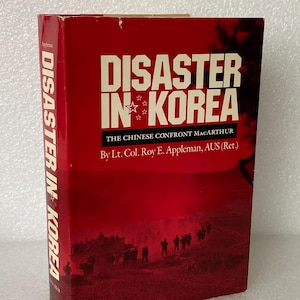 May include: A hardcover book titled "Disaster in Korea" with a red cover. The title is in large white letters with a star graphic. The book's spine also displays the title. The author is Lt. Col. Roy E. Appleman.