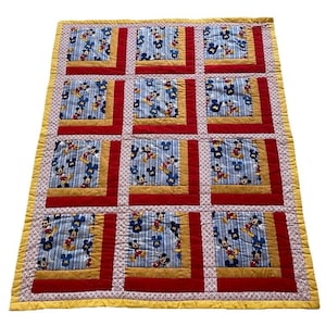 Pode incluir: Um edredom feito &agrave; m&atilde;o com um padr&atilde;o repetido do Mickey Mouse sobre um fundo listrado azul. O edredom tem bordas vermelhas e douradas e uma borda amarela estampada. O edredom &eacute; provavelmente para a cama ou o quarto de uma crian&ccedil;a.