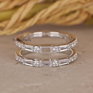 Puede incluir: Dos delicados anillos de plata con diamantes baguette y redondos. Los anillos están apilados uno encima del otro.