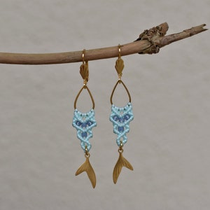 May include: Gold earrings with a blue and light blue macrame design and a gold fishtail charm.