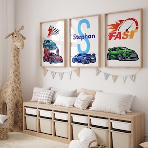 Op de afbeelding: Drie ingelijste prints met een raceautothema. De eerste print toont een rode raceauto met een geblokte vlag en het nummer één. De tweede print toont een blauwe letter S met de naam Stephan. De derde print toont een groene raceauto met het woord FAST en een snelheidsmeter.