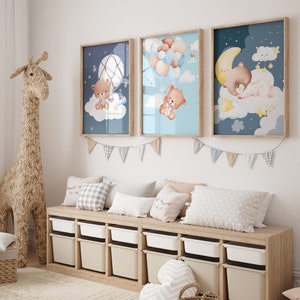May include: Three framed prints with a blue and white background featuring a cartoon bear in different scenes. The prints are hanging on a white wall above a wooden bench with storage bins and pillows.